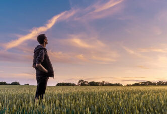 Our Story: Man in field watching the sunset